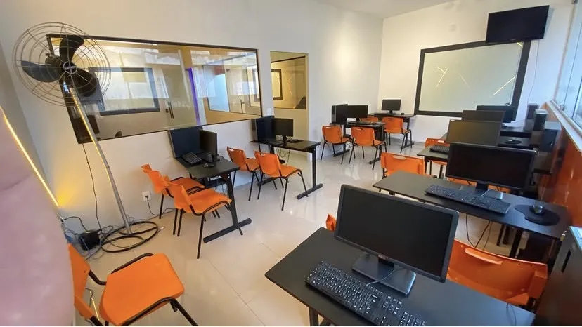 Computadores em mesas com cadeiras laranja