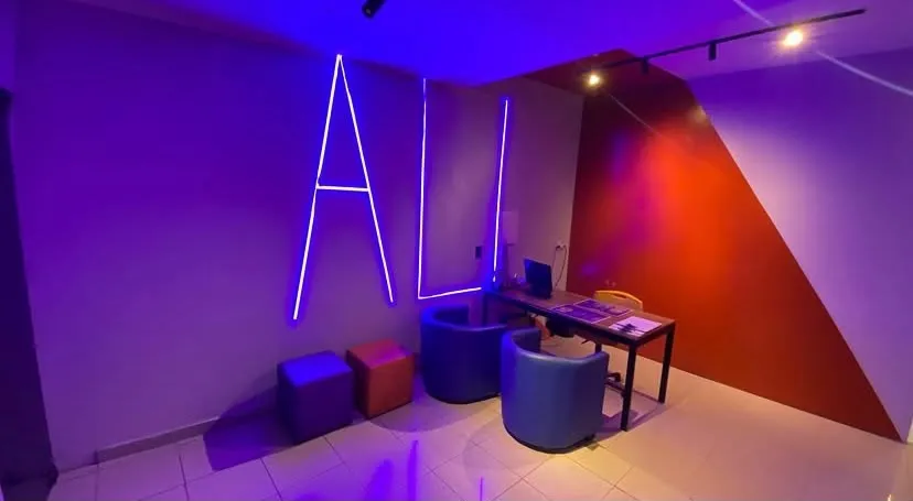 Recepção com luz azul, parede vermelha e poltronas azuis